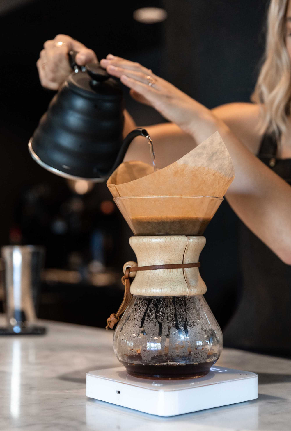 WOMAN POURING COFFEE WITH CHEMEX BONDED FILTERS PRE-FOLDED SQUARES
